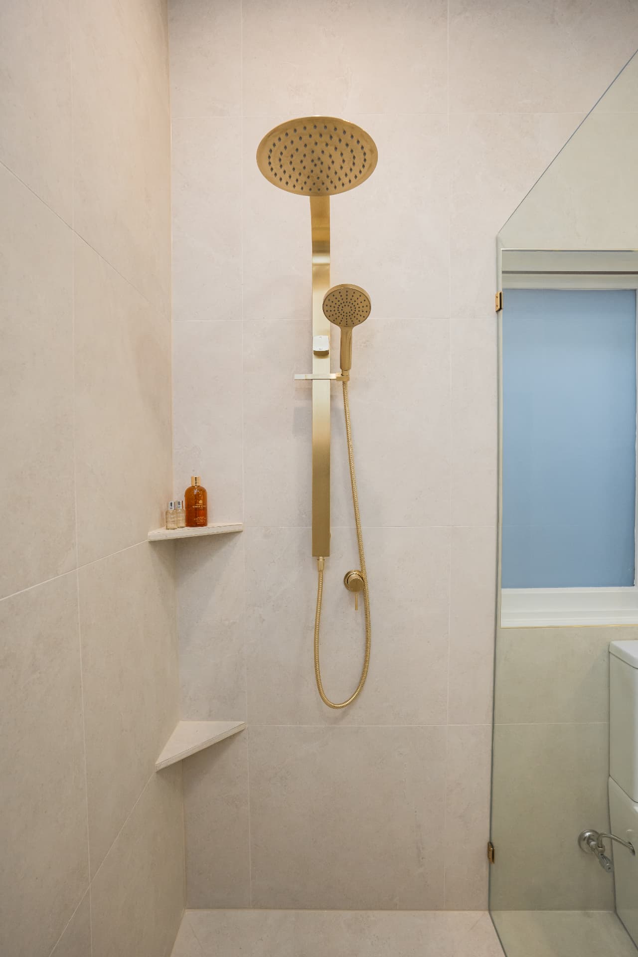 Tiled shower with brushed brass rail shower and mitred corner shelves