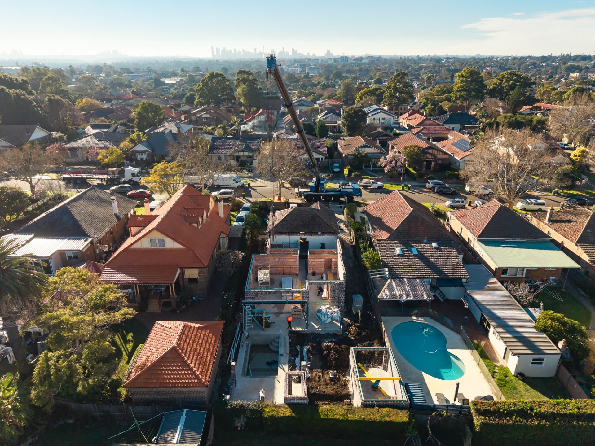 Aerial view of a high-end residential build with a crane on site and the Sydney skyline behind