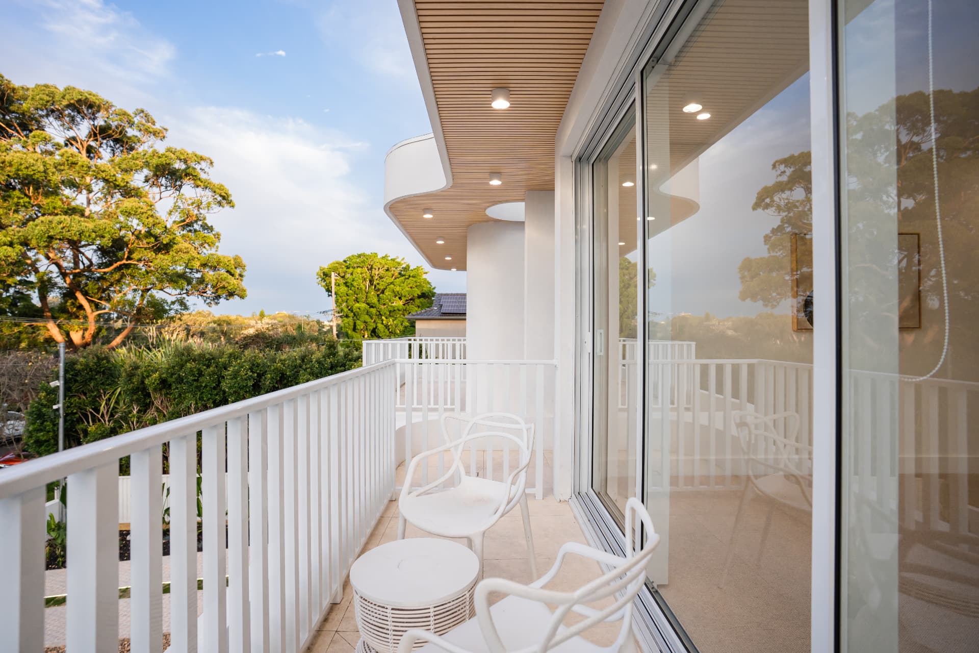 Upper balcony with battened timber soffit, white balustrade and treetop views
