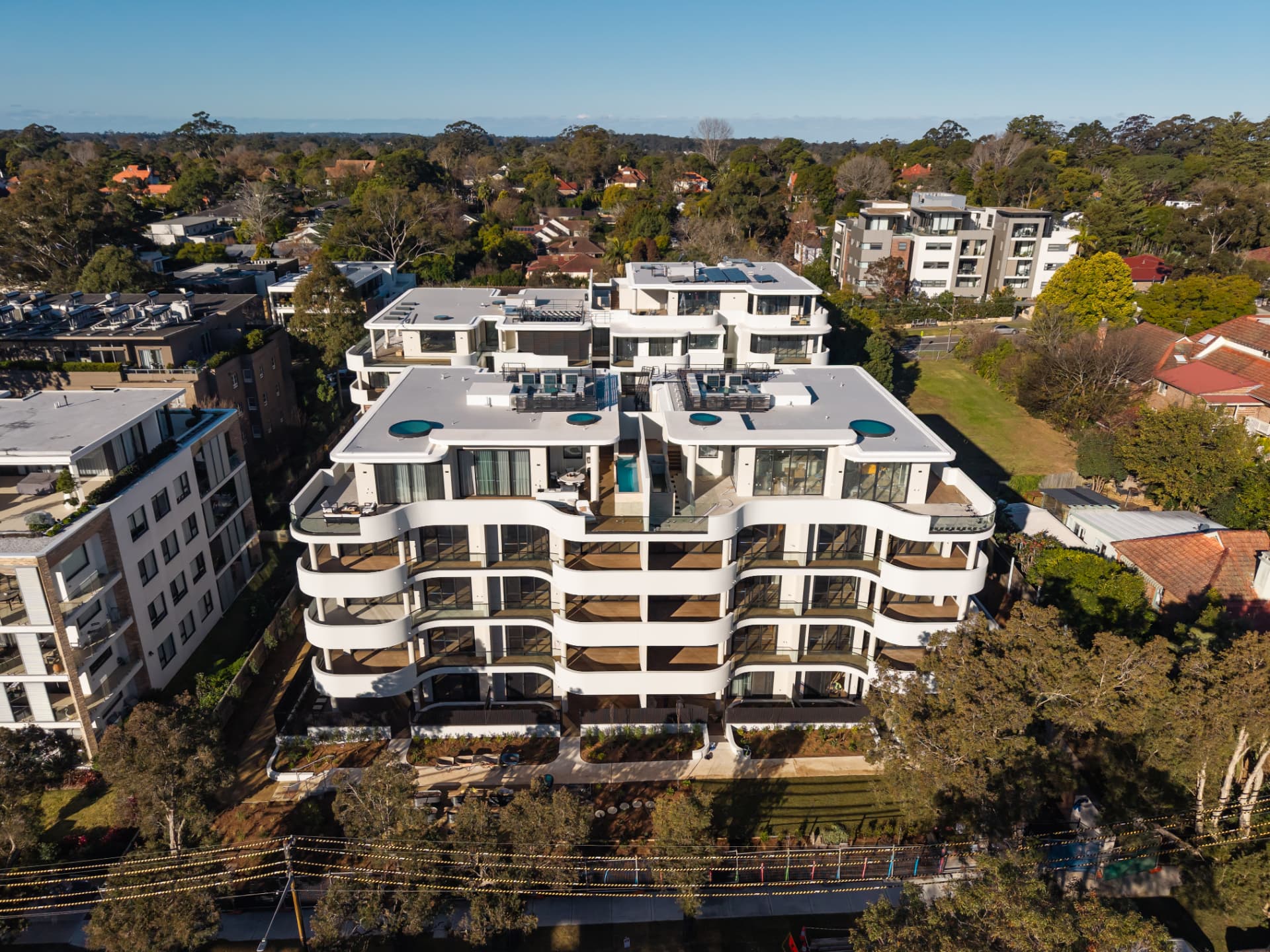 Aerial view of a curved white residential development finished with Acetech composite decking and aluminium facade systems
