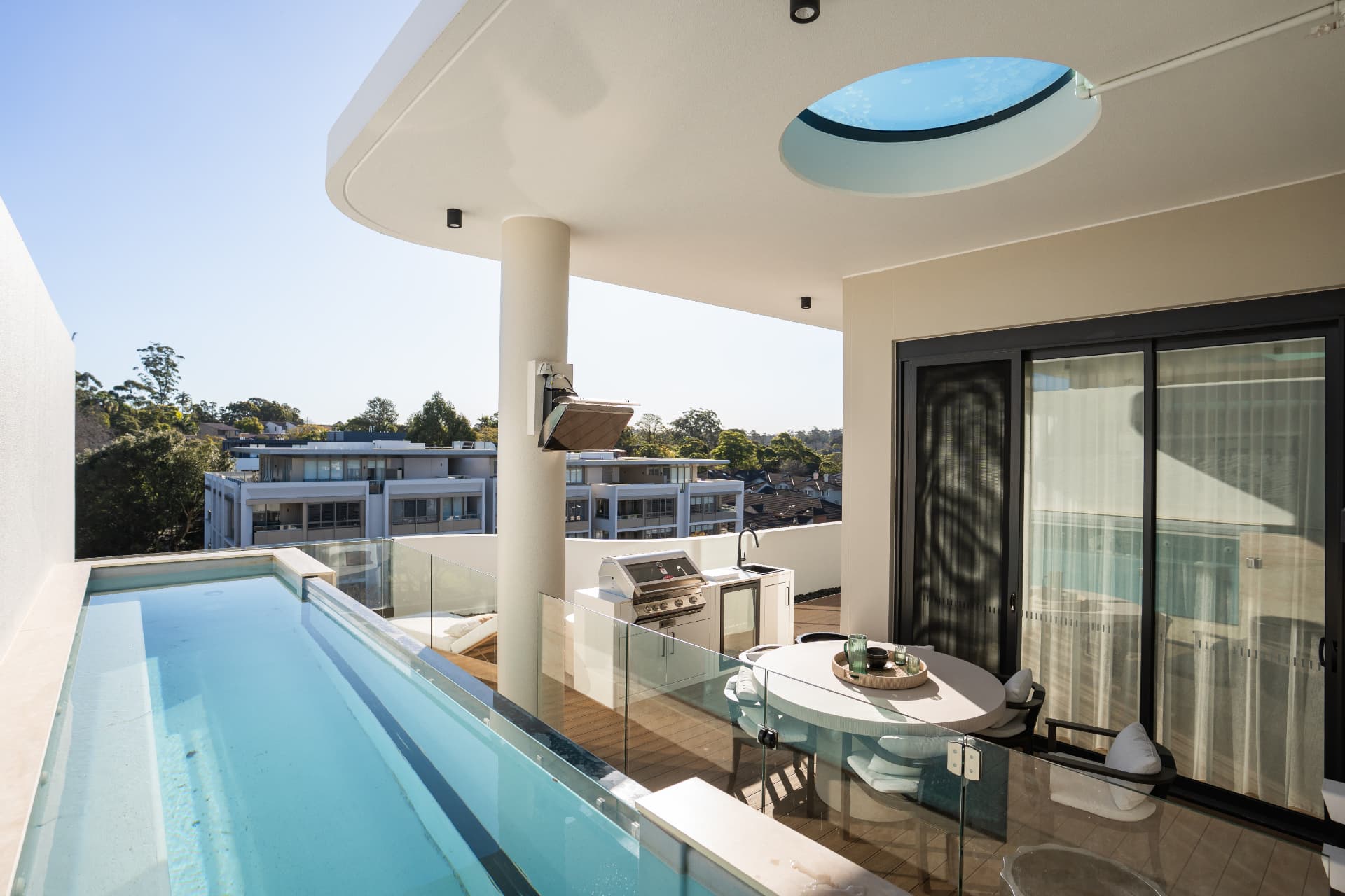Rooftop pool and dining terrace laid in composite decking with a circular skylight above