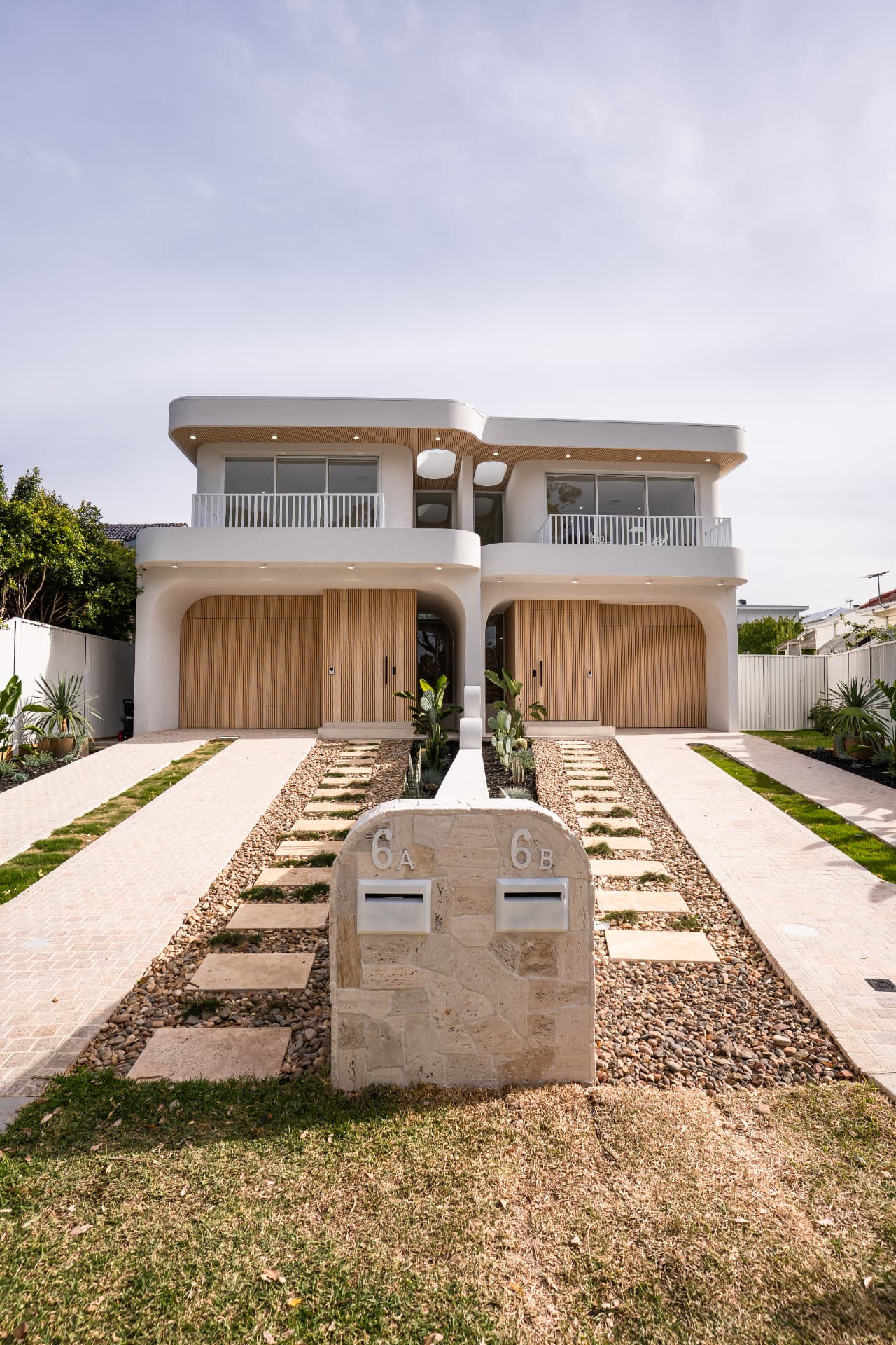 Straight-on view of the duplex frontage with sandstone letterbox, stepping stones and twin driveways