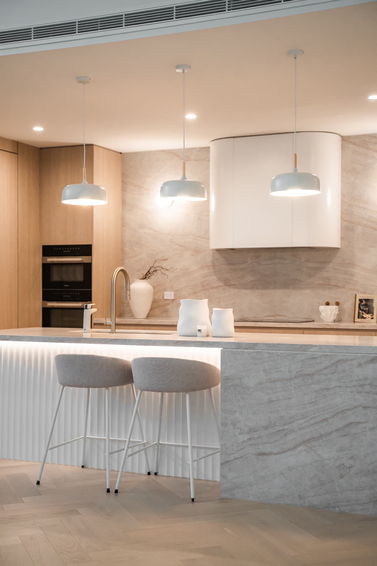 Detail of the stone island bench, fluted base with strip lighting and pendant lights over the sink