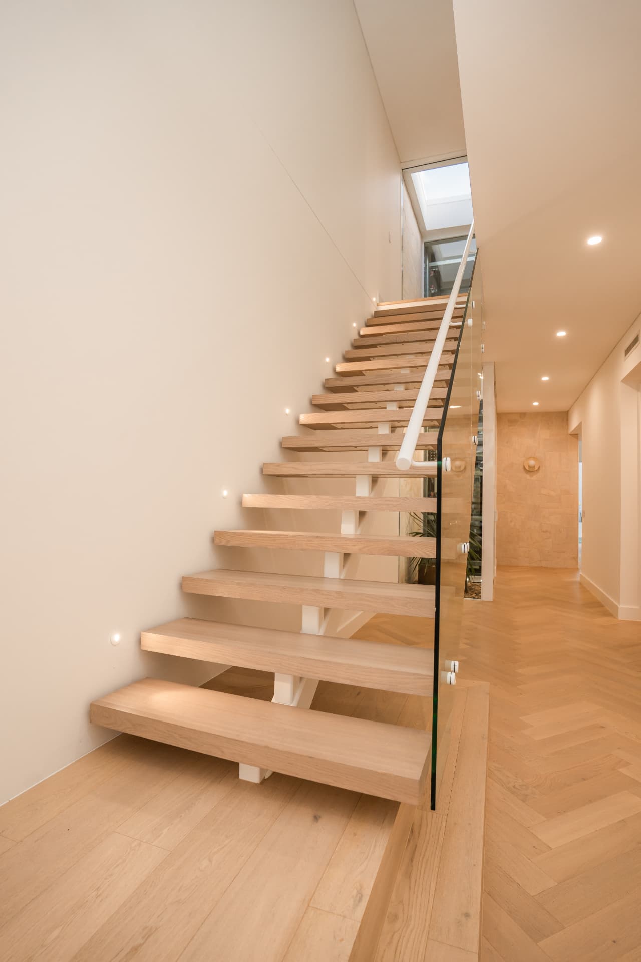 Floating oak stair with glass balustrade and a skylight above the flight