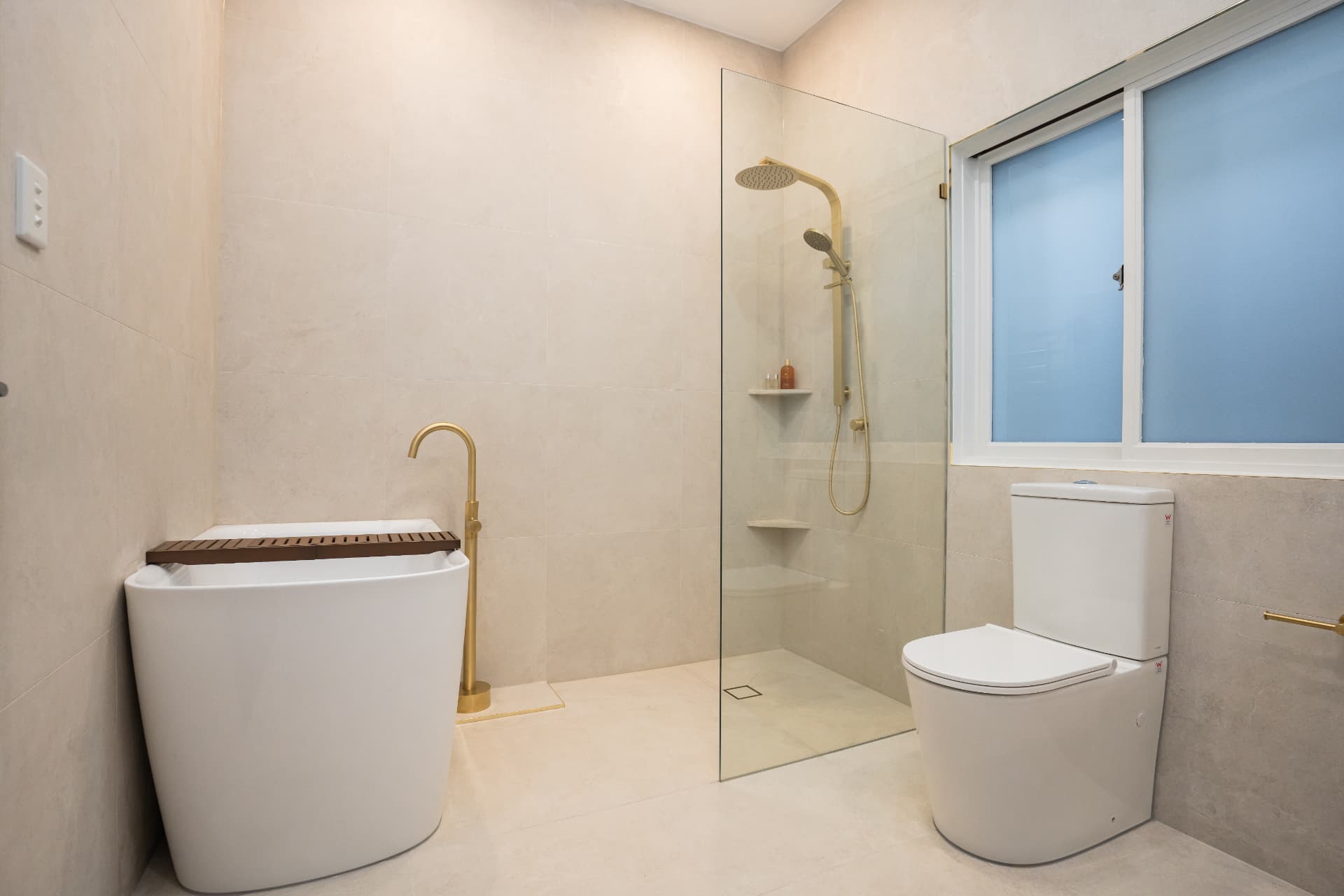 Finished bathroom renovation with freestanding bath, frameless shower and large-format stone-look tiles