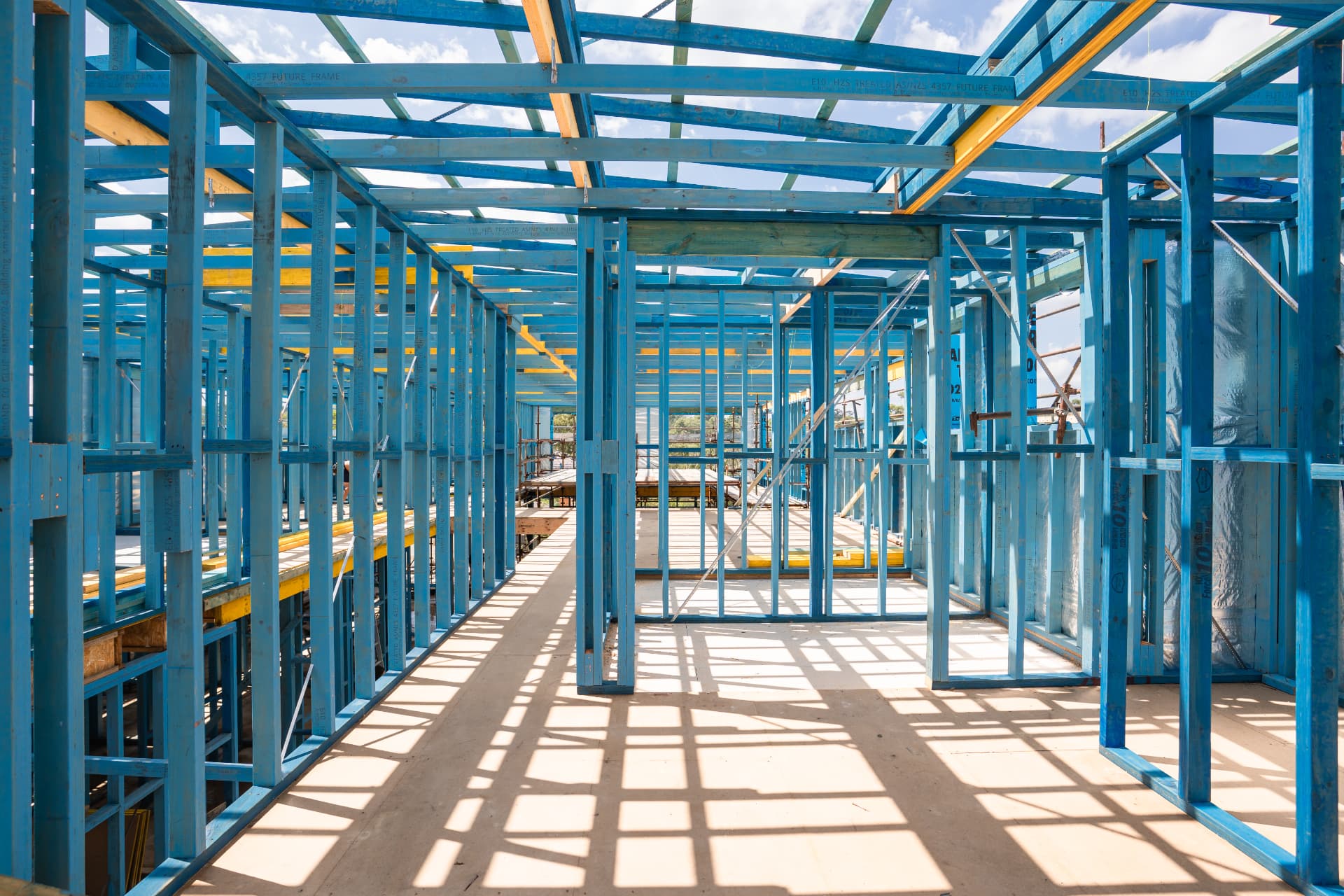 Interior of a blue-treated timber wall frame with LVL beams and roof framing overhead