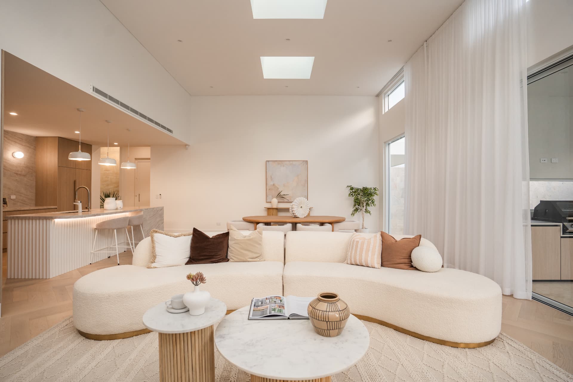 Open-plan living and kitchen with skylights, curved sofa and stone island beyond